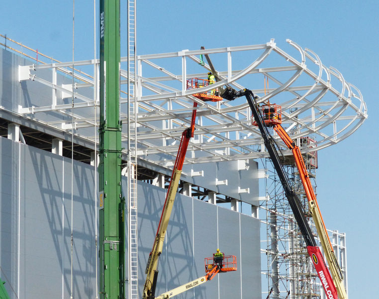 The cantilever round roof is being mounted along the façade of Experimental Hall 1.