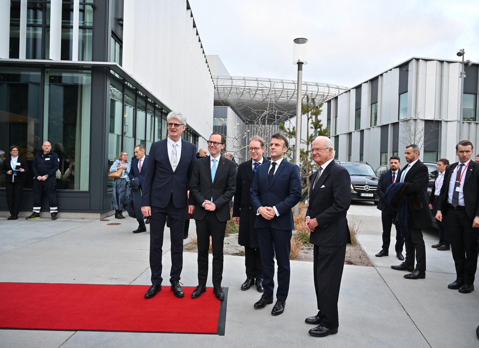ESS Director General Helmut Schober stands to the left of the King of Sweden, French President Emmanuel Macron, Swedish Minister of Education Mats Persson and Minister of Foreign Affairs Tobias Billström, by a red carpet outside the shiny glass office buildings of ESS