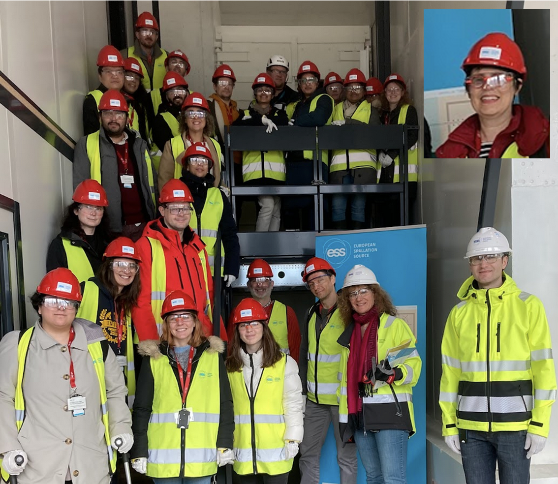 Around 20 people wearing high vis vests and red helmets stand smiling at a flight of industrial stairs, by a roll up with ESS branding